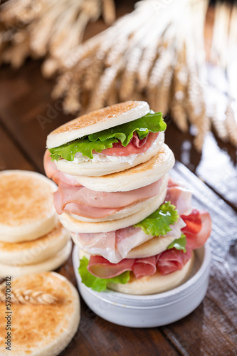 tigelle or crescentine homemade, con prosciutto, salame, stracciatella liquida. Italian food typical of the area of Modena, Emilia-Romagna. Thin round breads stuffed with prosciutto.  photo