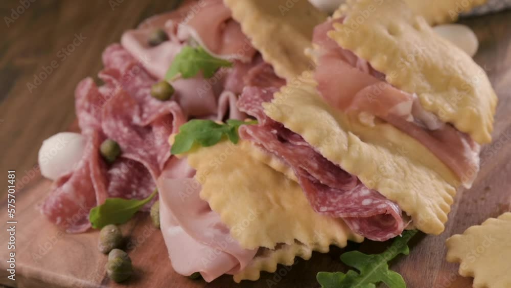 Crescentina. Food of Emilia Romagna region, deep fried bread gnocco fritto or crescentina. Starter or aperitif in Italy. Creshantina with prosciutto crudo, mortadella, Milanese salami, capers, cheese Crescentina. Food of Emilia Romagna region, deep fried bread gnocco fritto or crescentina. Starter or aperitif in Italy. Creshantina with prosciutto crudo, mortadella, Milanese salami, capers, cheese