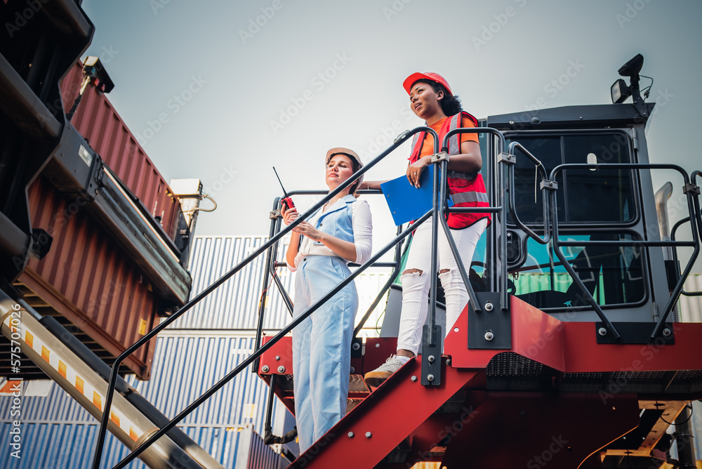 Caucasian engineer woman using a communication radio and African workers woman are working in containers industry, logistic transport Import-Export Cargo, to business shipping and warehouse concept. Caucasian engineer woman using a communication radio and African workers woman are working in containers industry, logistic transport Import-Export Cargo, to business shipping and warehouse concept.