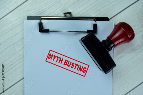 Concept of Red Handle Rubber Stamper and Myth Busting text isolated on on Wooden Table. photo