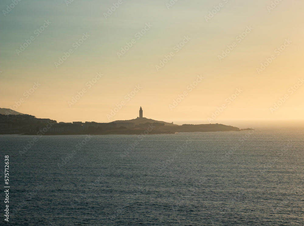 Tower of Hercules on the horizon, illuminated by the last rays of sunlight at sunset. Located in A Coruña, Galicia, and of historical interest, copy space.