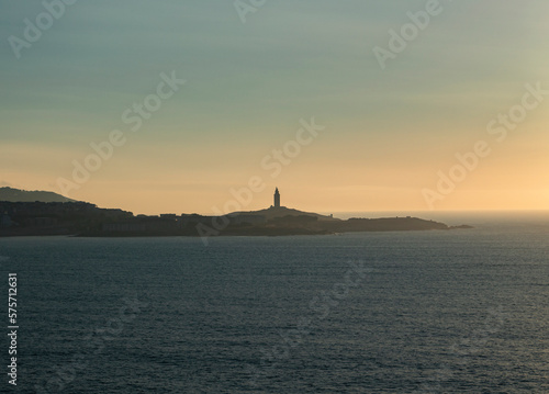 Tower of Hercules on the horizon, illuminated by the last rays of sunlight at sunset. Located in A Coruña, Galicia, and of historical interest, copy space.