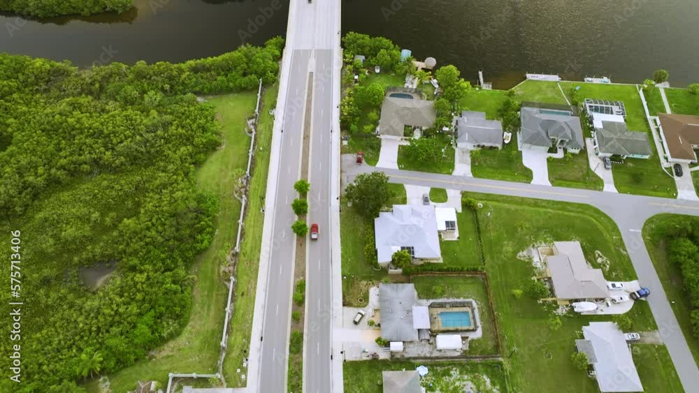 Aerial view of street traffic with driving cars in small town. American suburban landscape with private homes between green palm trees in Florida quiet residential area Aerial view of street traffic with driving cars in small town. American suburban landscape with private homes between green palm trees in Florida quiet residential area