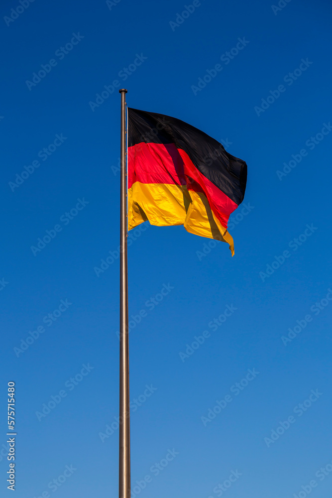 German flag on a flagpole against the blue sky German flag on a flagpole against the blue sky