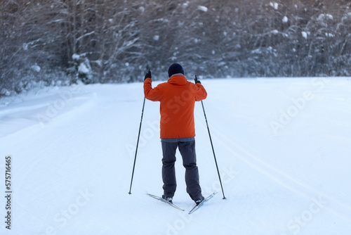 A man goes cross-country skiing in winter through the forest on a special track.