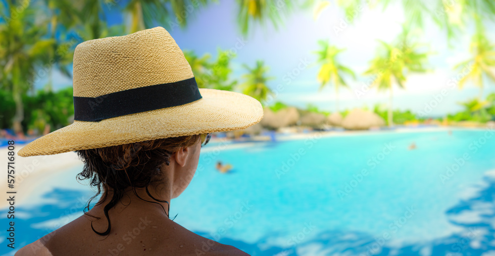 Woman with sunhat looking at the swimming pool in a spa resort.