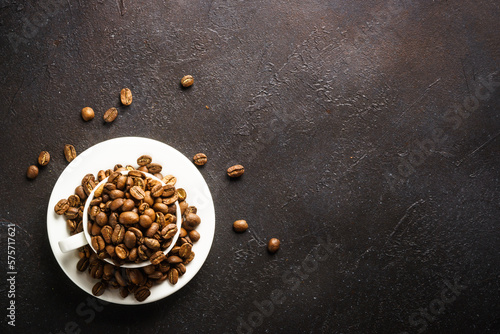 Coffee cup. Roasted coffee beans in white cup at dark table. Top view image.