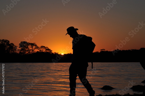 silhouette of a male explorer with hat and backpack