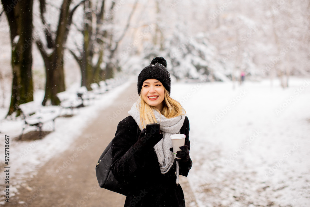 Young woman with Warm Clothes in Cold Winter Snow drinking coffee to go Young woman with Warm Clothes in Cold Winter Snow drinking coffee to go