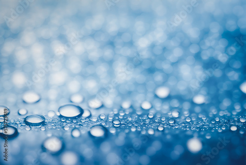 Droplet is perched delicately on a smooth surface with a background of sparkling bokeh lights.