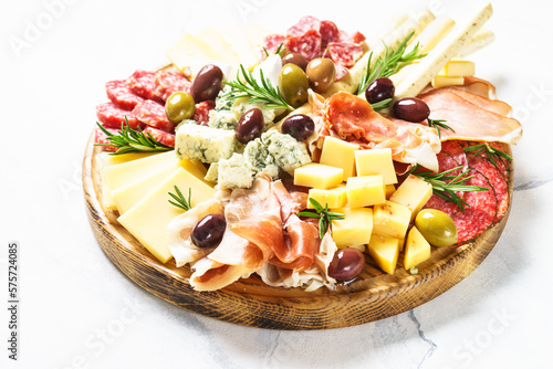 Antipasto platter. Cheese and meat - jamon, salami, olives at wooden serving board.