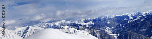 Panorama of off-piste snowy slope and cloudy mountains © BSANI