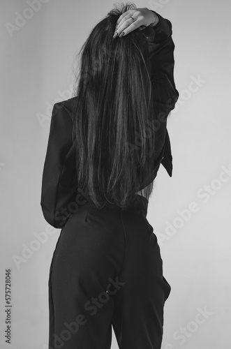 Unrecognizable young woman in a black jacket on her shoulder, rear view