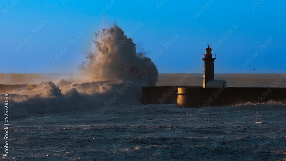 View of the lighthouse with a stormy Atlantic wave during a beautiful sunset, Porto, Portugal.