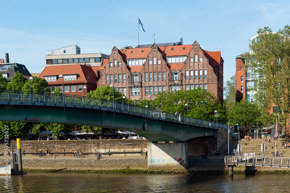 Fototapeta premium Cityscape of Bremen with old architecture, historical wooden sailing ships and barge floating along the river Weser. Bremen, Germany, July 15, 2021
