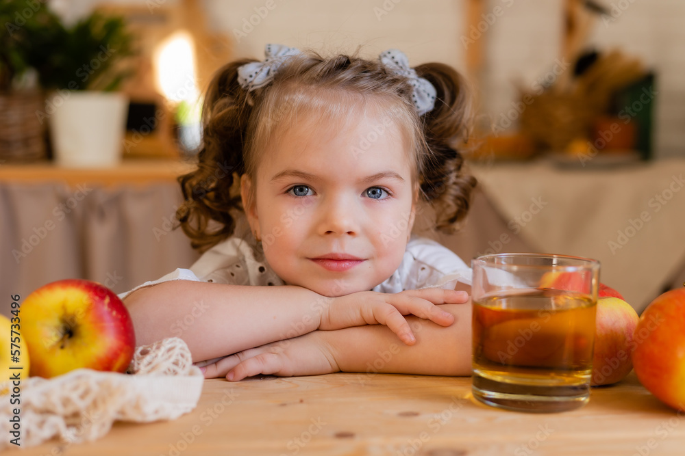 cute little girl in the kitchen at home with apples and a glass of apple juice. Eco-friendly food for children. Space for text cute little girl in the kitchen at home with apples and a glass of apple juice. Eco-friendly food for children. Space for text