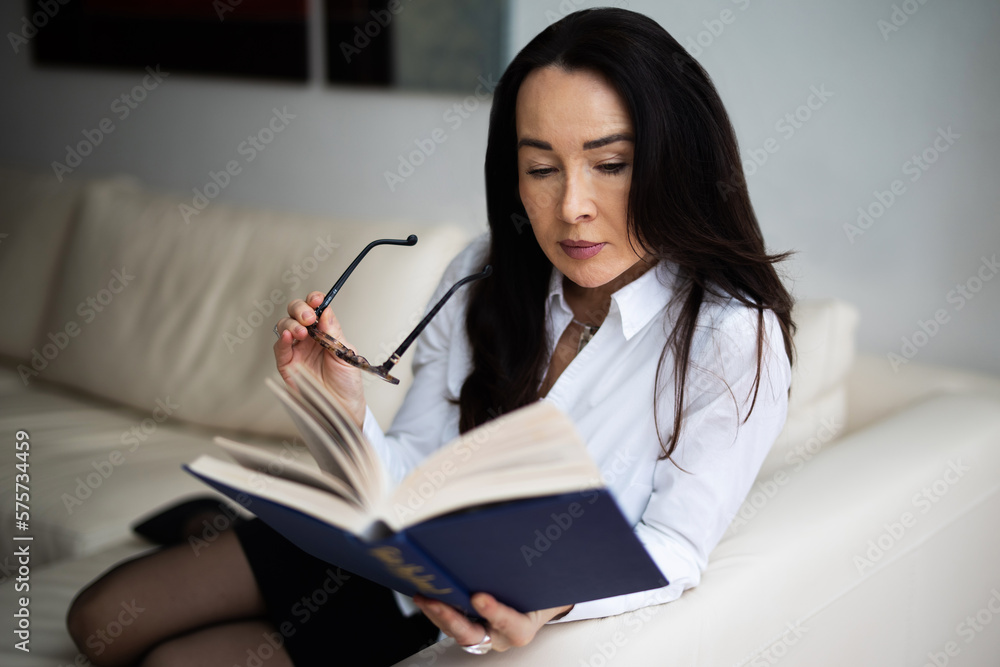 Attraktive Frau sitzt entspannt auf der Couch und liest ein Buch Attraktive Frau sitzt entspannt auf der Couch und liest ein Buch
