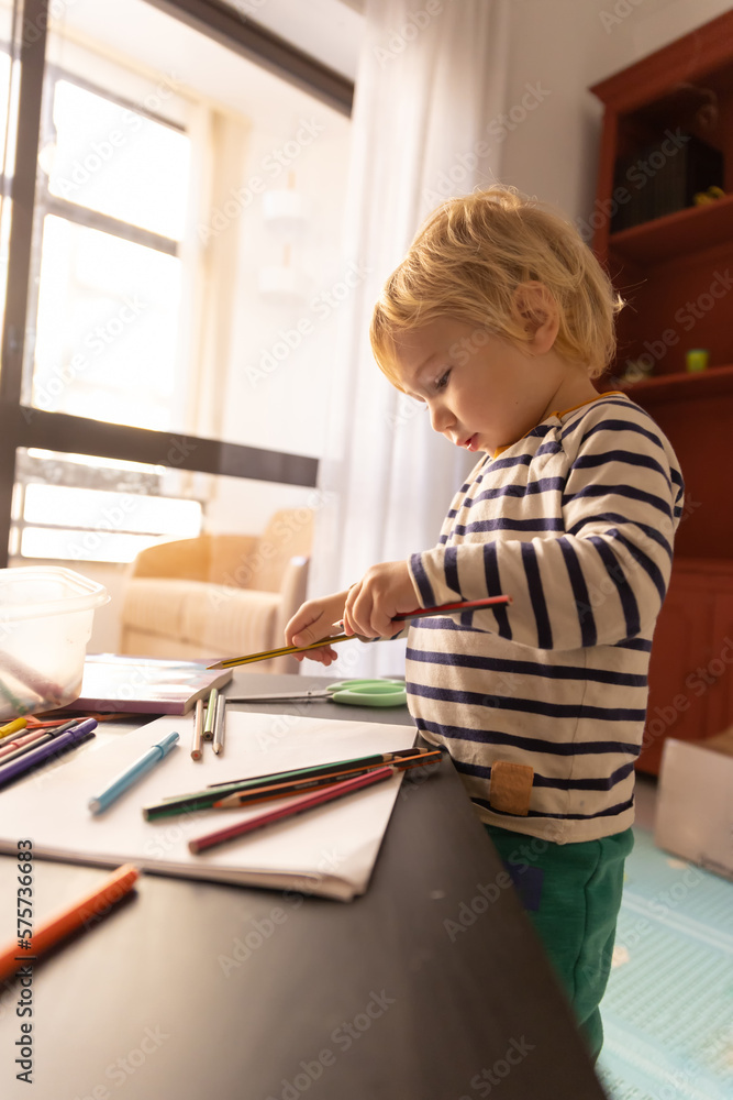 Cute little blonde boy playing with color pencils Cute little blonde boy playing with color pencils