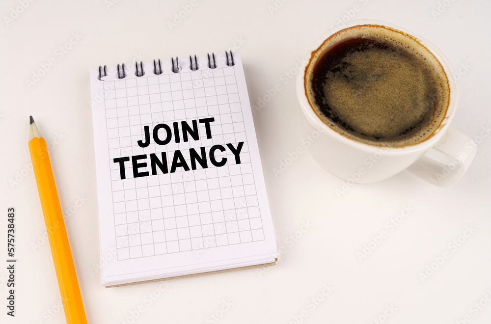 On a white surface, a cup of coffee, a pencil and a notepad with the inscription - JOINT TENANCY On a white surface, a cup of coffee, a pencil and a notepad with the inscription - JOINT TENANCY