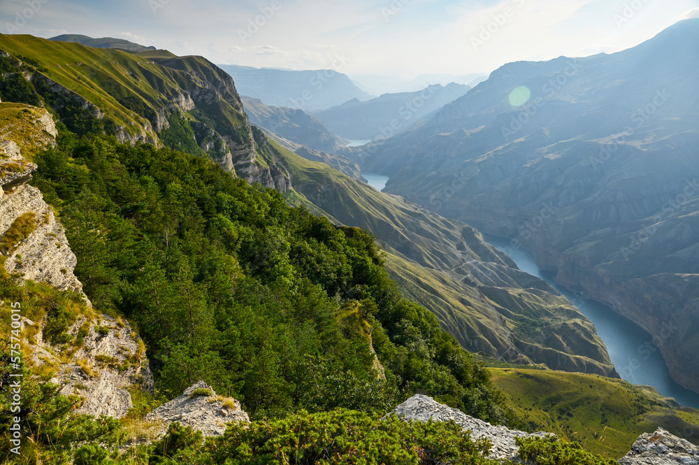 A beautiful landscape of mountains with bushes, rocks and a blue river on a summer day at sunset. Sulak Canyon.