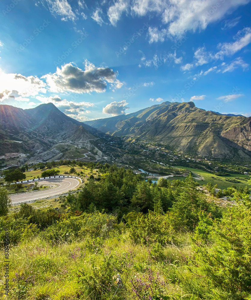  Beautiful view of the valley in the mountains with a road and a river on a sunny summer day. Dagestan