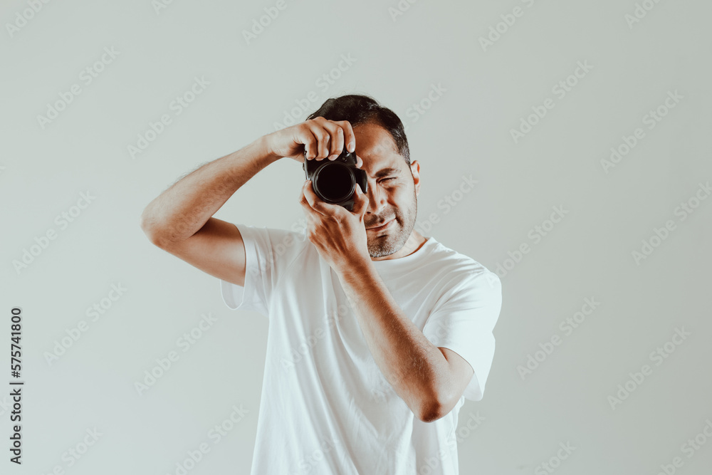 Male photographer taking a picture on a light background. Concept of technology, professions, lifestyles and arts. Male photographer taking a picture on a light background. Concept of technology, professions, lifestyles and arts.