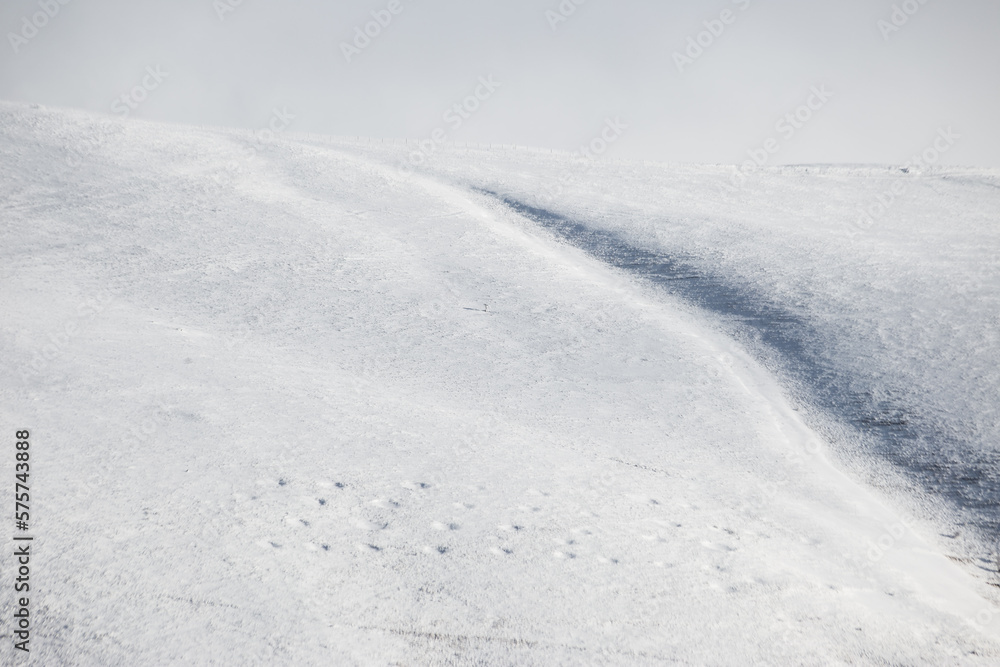 Minimalistic, almost empty view of snow in the mountains, with some barely visible footprints