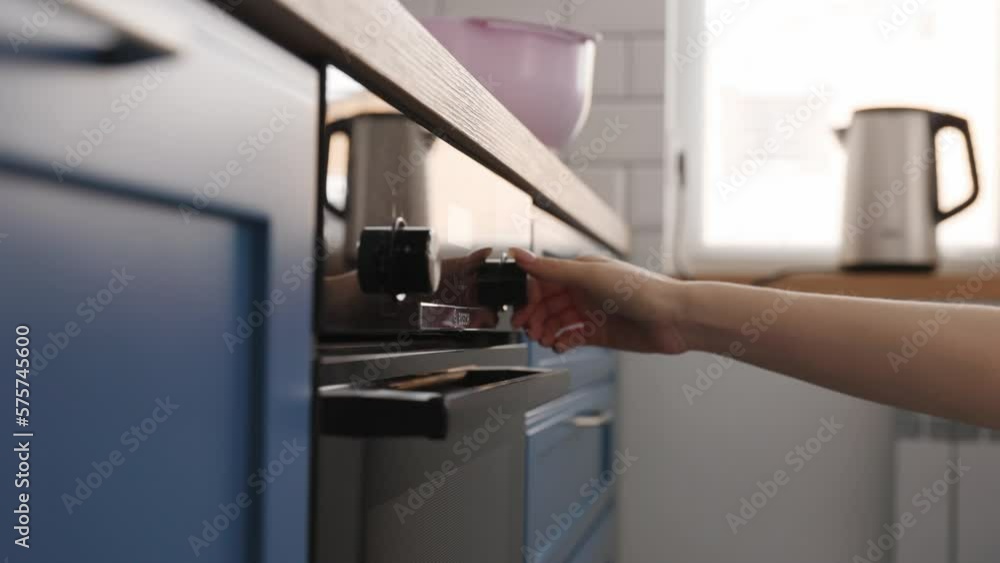 The girl turns on the oven in the kitchen The girl turns on the oven in the kitchen
