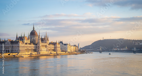 Hungarian Parliament and Danube river at sunset. Beautiful evening sky with pastel pink and orange colors. Panoramic view.