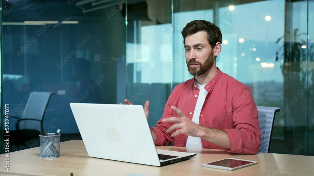 mature bearded businessman entrepreneur talking online on video call sitting in office at workplace Male freelancer employee holding conference webinar or virtual meeting speak in a red shirt Indoor mature bearded businessman entrepreneur talking online on video call sitting in office at workplace Male freelancer employee holding conference webinar or virtual meeting speak in a red shirt Indoor