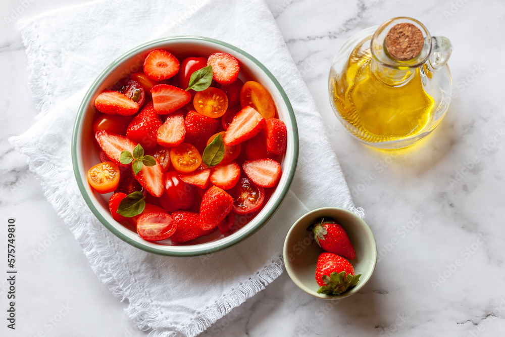 Portion of strawberry and tomato cherry salad decorated with basil leaves Portion of strawberry and tomato cherry salad decorated with basil leaves