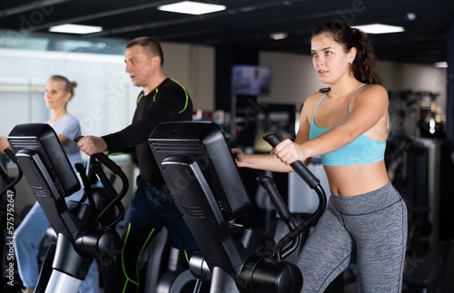 Fit young woman working out at elliptical machine in gym