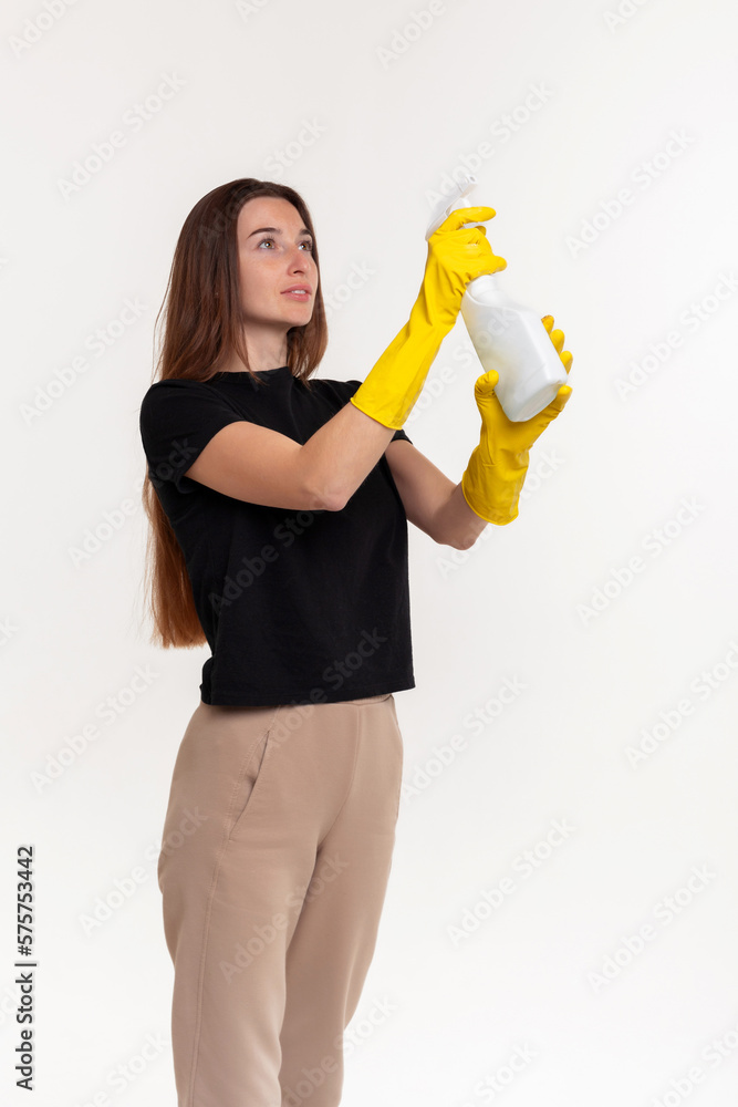 Girl with a sprayer in rubber yellow gloves on a white background. Disinfection, moisturizing. Girl with a sprayer in rubber yellow gloves on a white background. Disinfection, moisturizing.