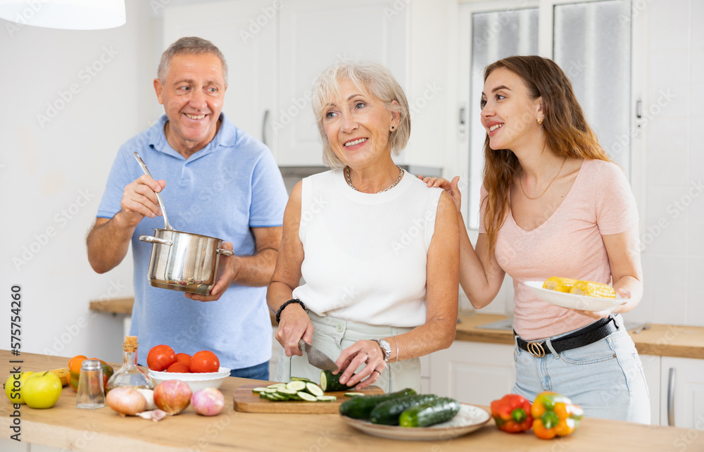 Portrait of smiling mature man, woman and daughter preparing family dinner at kitchen table