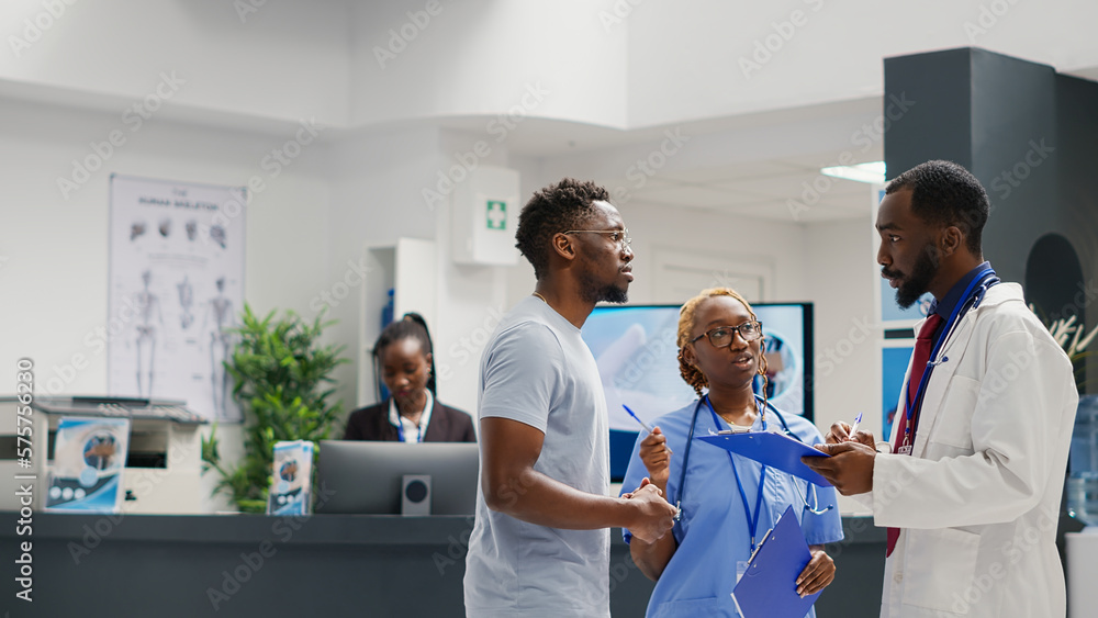 Obraz premium Medic and nurse discussing about treatment with male patient, preparing to do checkup consultation at clinic. Team of health specialists giving medical advice to sick man in hospital waiting room.