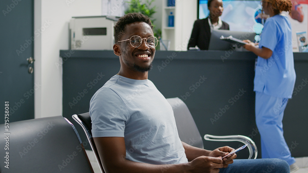 African american man waiting in hospital lobby, sitting in waiting room before attending checkup appointment with medic. Patient in facility reception having consultation with specialist. African american man waiting in hospital lobby, sitting in waiting room before attending checkup appointment with medic. Patient in facility reception having consultation with specialist.