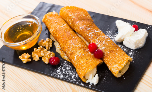 Thin pancakes in Bulgarian style (Palatschinke) filled with brynza served with honey, walnuts and cranberries photo