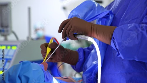 Doctor’s hands in brown latex gloves shoves electric tool in the patient’s nasal cavity. Surgeon performing rhinoplasty close up. photo