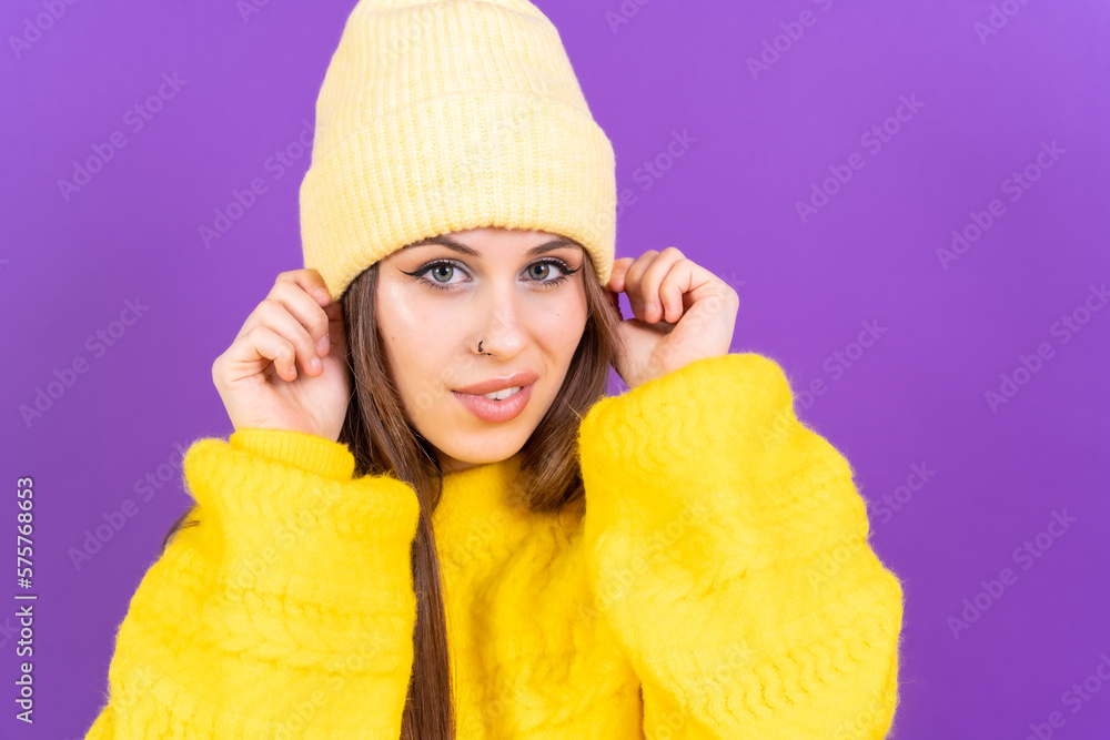 Close up portrait of young caucasian woman in yellow sweater isolated on yellow background, wearing wool cap Close up portrait of young caucasian woman in yellow sweater isolated on yellow background, wearing wool cap