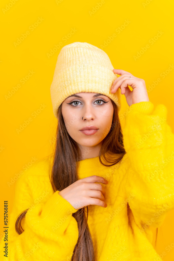 Close up portrait of a young caucasian woman in wool sweater isolated over yellow background, looking at camera Close up portrait of a young caucasian woman in wool sweater isolated over yellow background, looking at camera