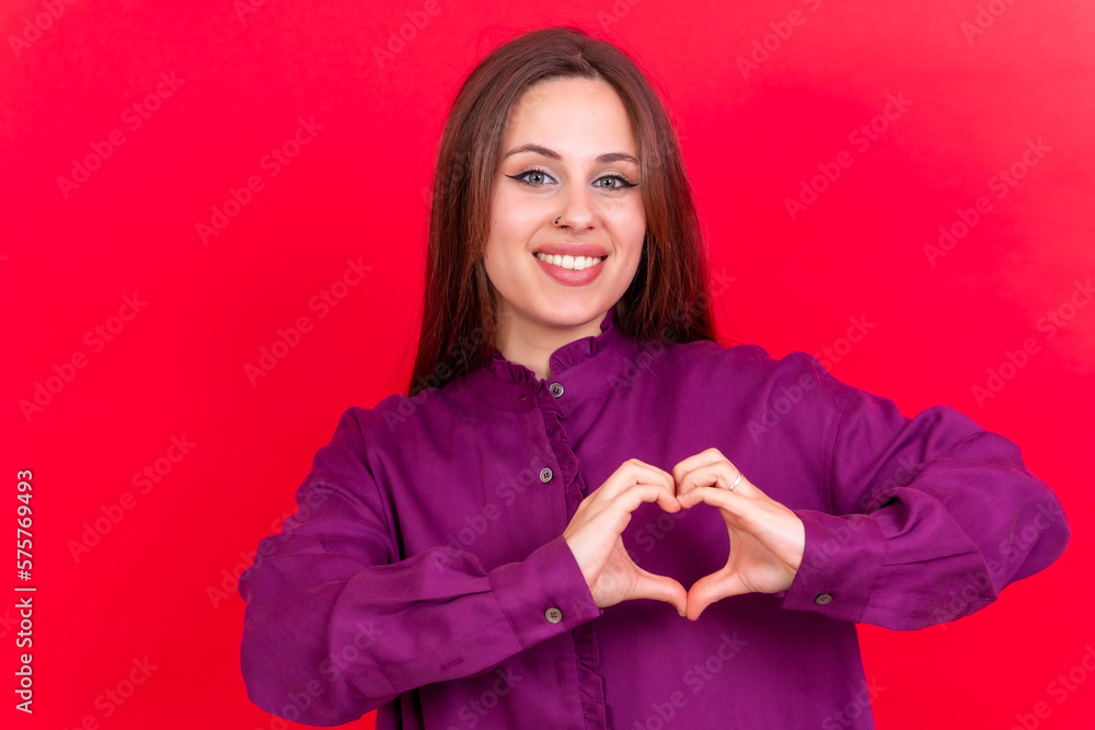 Young brunette woman wearing purple sweater over isolated red background smiling in love making heart symbol shape with hands. romantic concept Young brunette woman wearing purple sweater over isolated red background smiling in love making heart symbol shape with hands. romantic concept