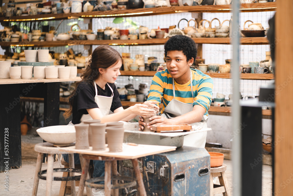 An Afro-haired potter sculpts a ceramic pot from clay on a potter's wheel. Art workshop concept, hands with clay making of a ceramic pot on the pottery wheel, hobby and leisure with pleasure concept