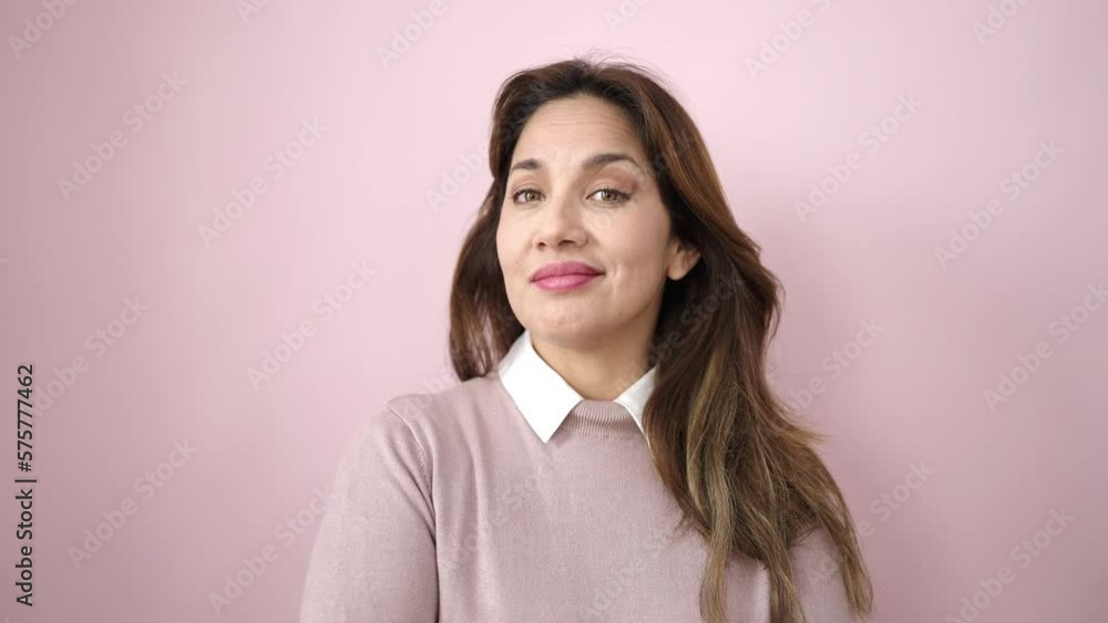 Young beautiful hispanic woman smiling confident moving the head over isolated pink background Young beautiful hispanic woman smiling confident moving the head over isolated pink background