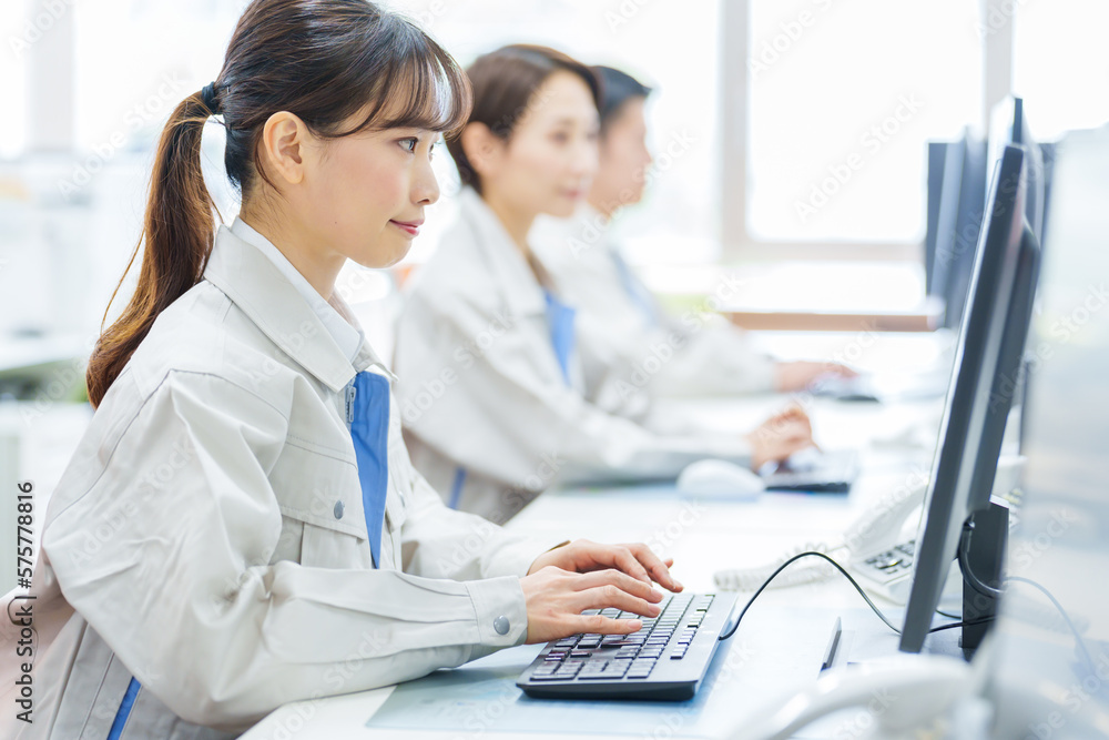 オフィスでデスクワークをする作業服を着た女性