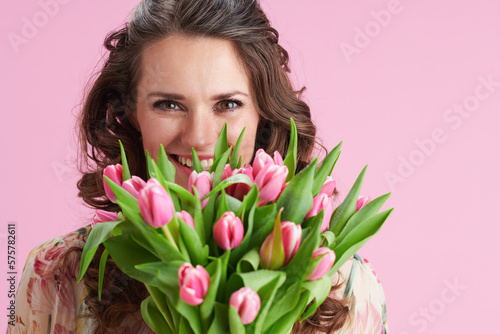 Portrait of smiling trendy woman in floral dress on pink