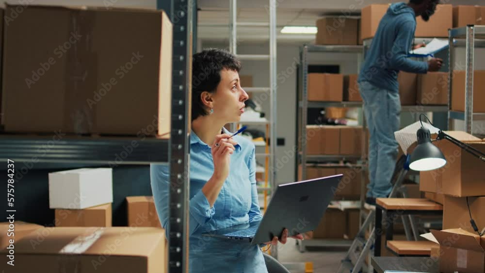 Warehouse owner checking cardboard boxes from storage space shelves, using laptop to plan stock inventory and take notes. Entrepreneur working on startup development and supply chain. Warehouse owner checking cardboard boxes from storage space shelves, using laptop to plan stock inventory and take notes. Entrepreneur working on startup development and supply chain.