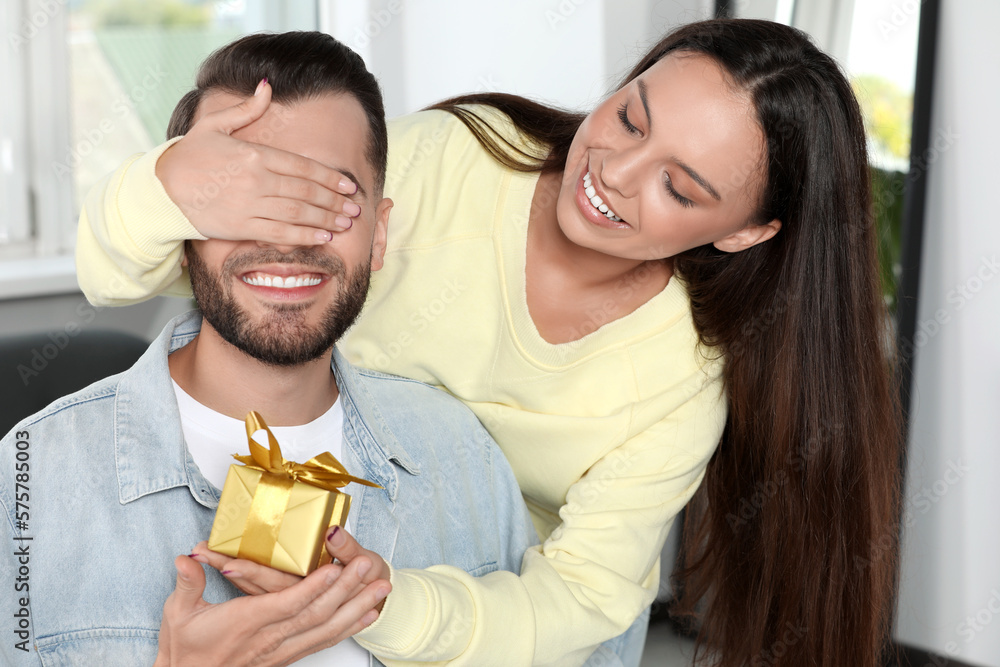 Woman presenting gift to her boyfriend at home Woman presenting gift to her boyfriend at home