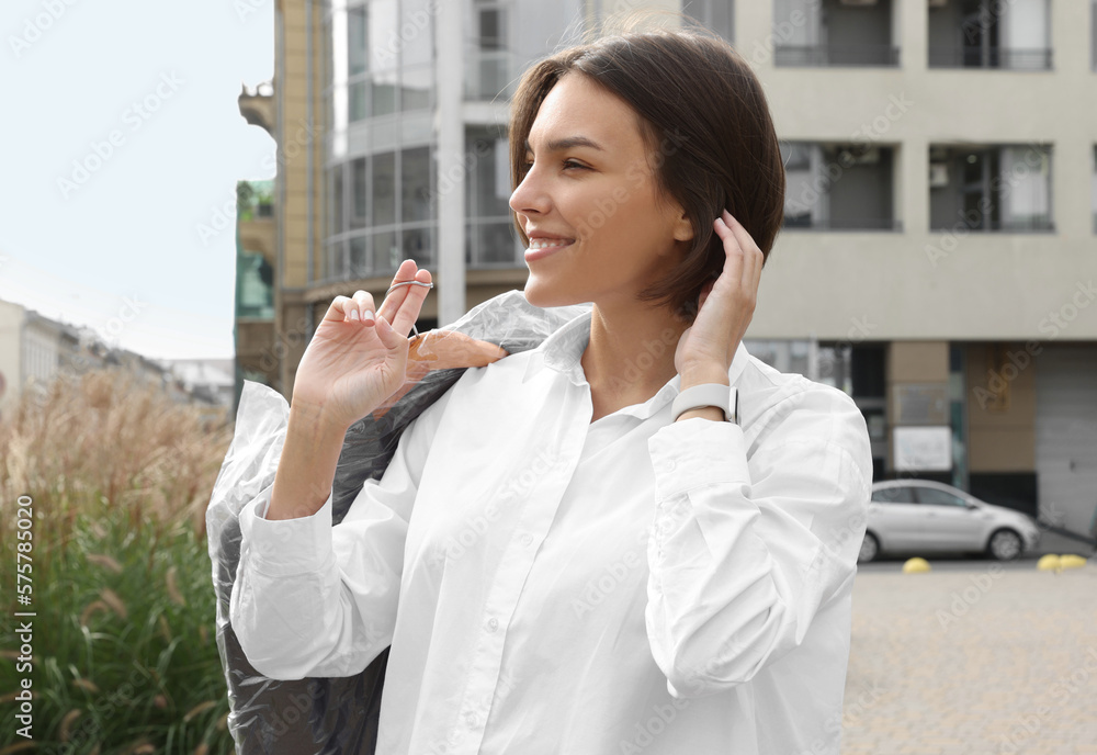 Woman holding garment cover with clothes outdoors. Dry-cleaning service Woman holding garment cover with clothes outdoors. Dry-cleaning service