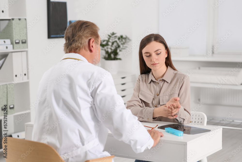 Orthopedist examining patient with injured hand in clinic Orthopedist examining patient with injured hand in clinic
