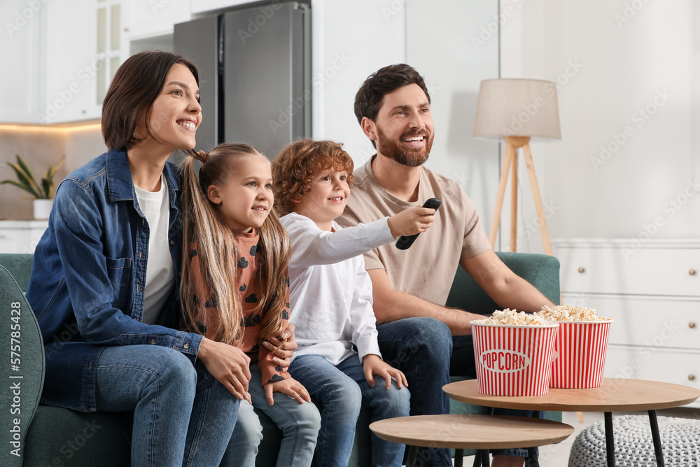 Happy family watching TV with popcorn on sofa at home
